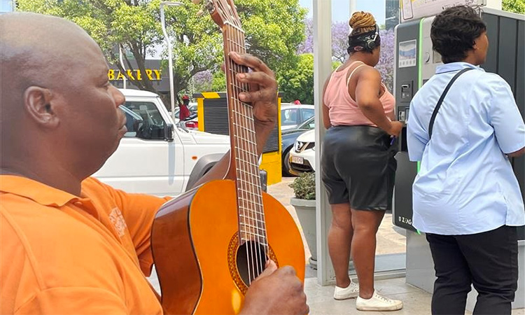 Thomas Nhassavele plays a guitar alongside a parking pay point in Rosebank Mall in Johannesburg, South Africa. Reuters