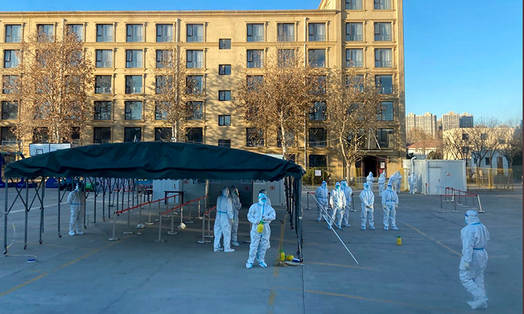 Workers in protective clothing prepare to receive passengers from a flight coming from outside China to be quarantined at a resort on the outskirts of Beijing on Thursday. Associated Press