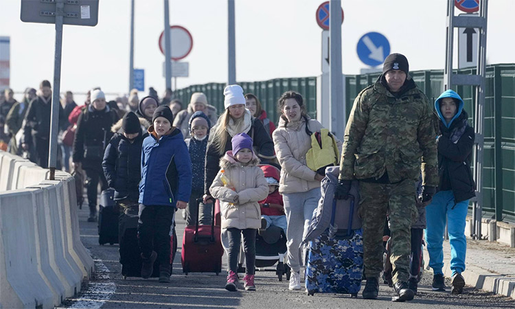 A Polish border guard assists refugees from Ukraine at the Korczowa border crossing. AP