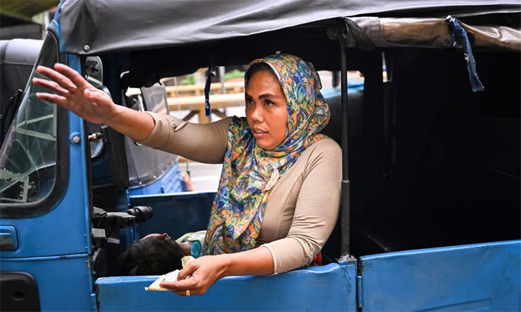 Ekawati, who plies her three-wheeled taxi in a profession overwhelmingly dominated by men in Indonesia's capital, gestures as she solicits customers while on her rounds in Jakarta. AFP