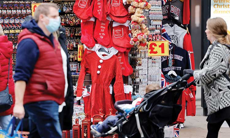 People walk past Christmas-themed items displayed for sale at a stall in London on Tuesday.   Agence France-Presse