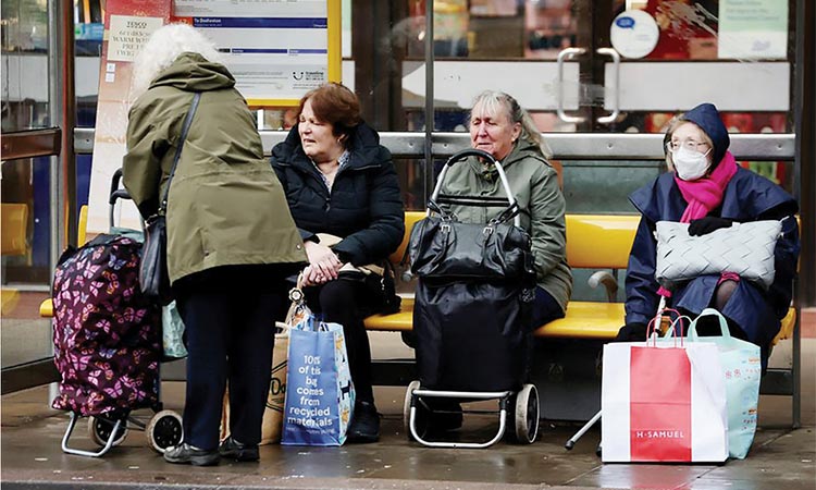 Women sit with shopping trolleys at a bus stop in Chester, Britain. Reuters