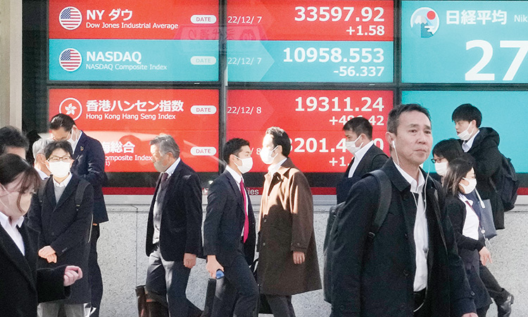 People walk past an electronic stock board showing global stock indexes in front of a securities firm in Tokyo, Japan.  Associated Press