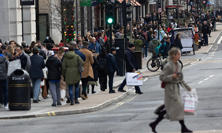 People carry shopping bags during the bank holiday sale in central London.  Agence France-Presse