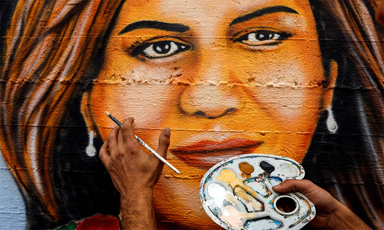 An artist applies final touches to a mural that he painted to pay tribute to Shireen Abu Akleh. Reuters