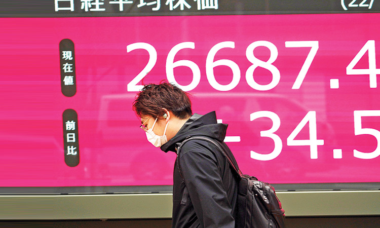 A man walks in front of an electronic stock board showing Japan’s Nikkei 225 index at a securities firm on Friday. Associated Press