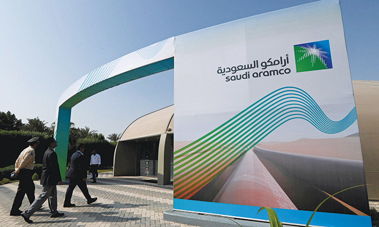 People walk past the logo of Aramco at the Plaza Conference Centre in Dhahran.