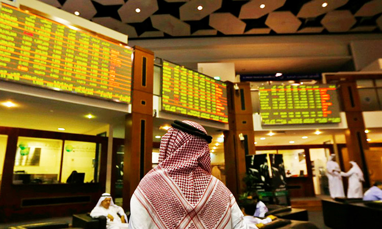An investor looks up at screens displaying stock information at the Dubai Financial Market.  File/Reuters