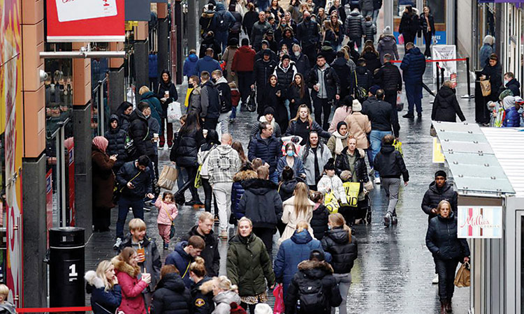 People walk along a busy shopping street in Liverpool, Britain.