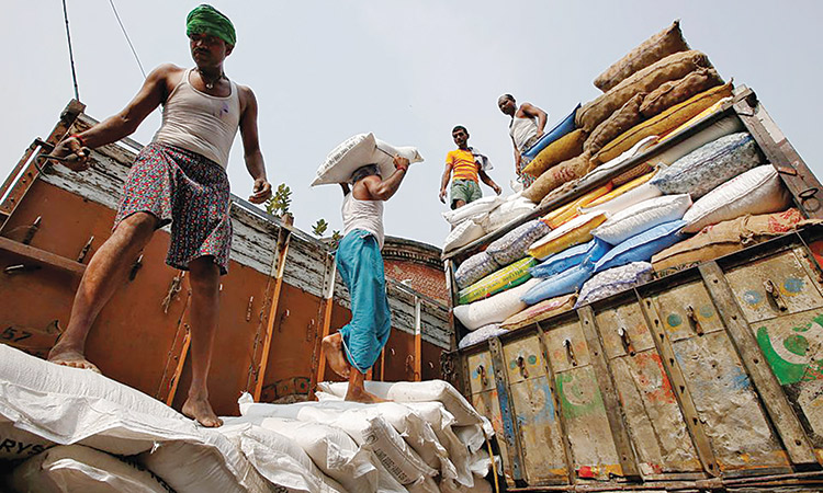 A labourer carries a sack filled with sugar to load it onto a supply truck at a wholesale market in Kolkata.  File/Reuters