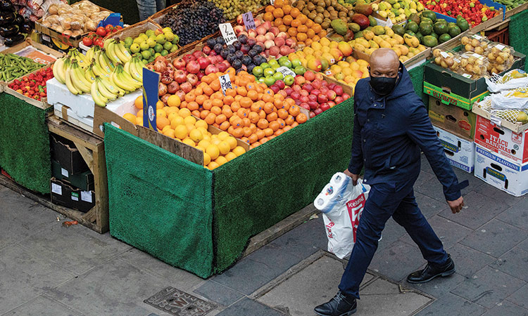 A man walks past a fruit and vegetable shop at Brixton Market in London, Britain. Reuters
