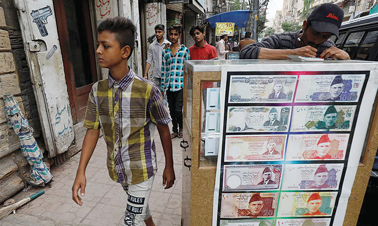 A boy walks past a sidewalk money exchange stall decorated with pictures of banknotes in Karachi, Pakistan. Reuters