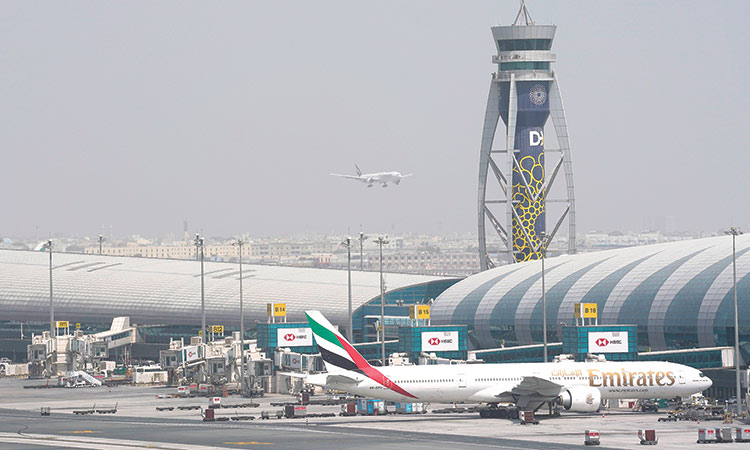 An Emirates Boeing 777 stands at a gate at the Dubai International Airport as another prepares to land on the runway in Dubai on Wednesday.  Associated Press