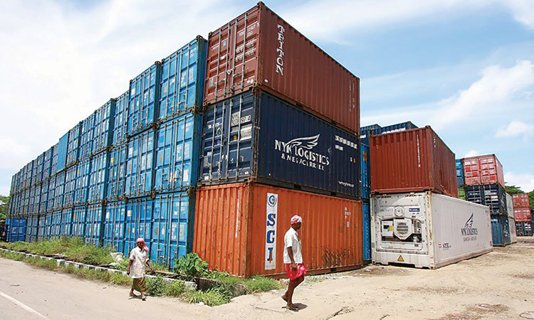 Workers walk past containers at a depot on Willingdon Island in the southern Indian city of Kochi.  File/Reuters