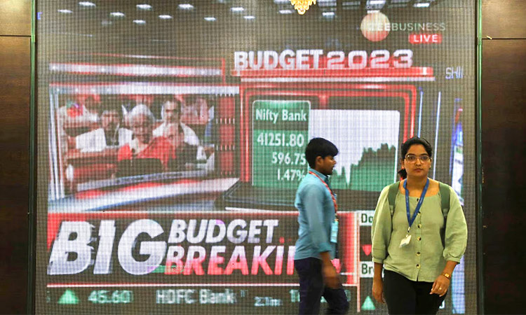 People pass by a giant screen which splashes news of Indian budget at a market in Mumbai. Reuters
