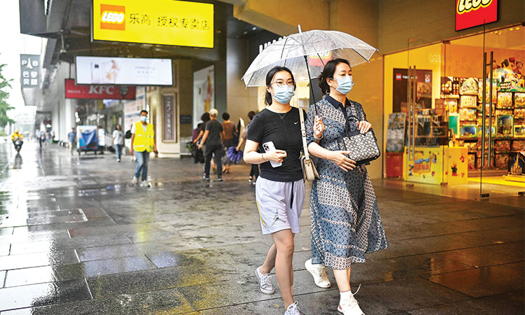 People use an umbrella as they walk past a store on a rainy day in Beijing on Thursday. AFP
