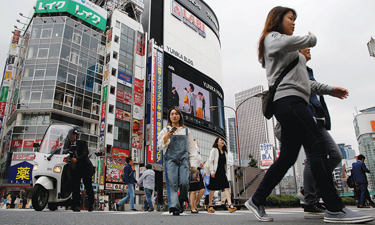 People cross a street in the Shinjuku shopping and business district in Tokyo, Japan.  Reuters