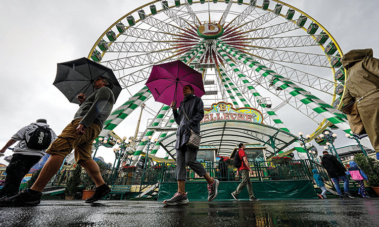 People under umbrellas walk in the rain at the first day of the Cranger Kirmes in Herne, Germany on Thursday. Associated Press