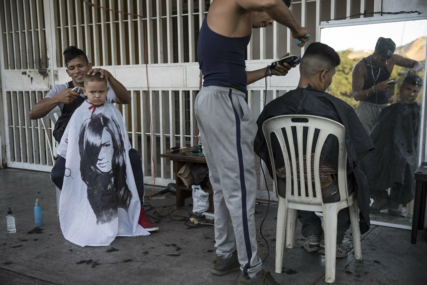 Juan Manuel Marquez, 32, left, cuts the hair of Jean Pierre, 4, at a makeshift barber shop on a sidewalk in Caracas, Venezuela.
