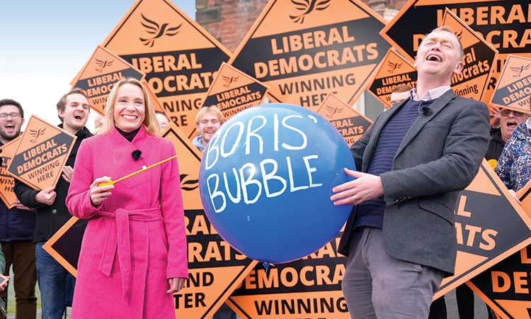 Newly-elected Liberal Democrat lawmaker Helen Morgan (left) bursts ‘Boris’ bubble,’ held by colleague Tim Farron, as she celebrates in Oswestry, Shropshire, England, on Friday following her victory  in the North Shropshire by-election.   Associated Press