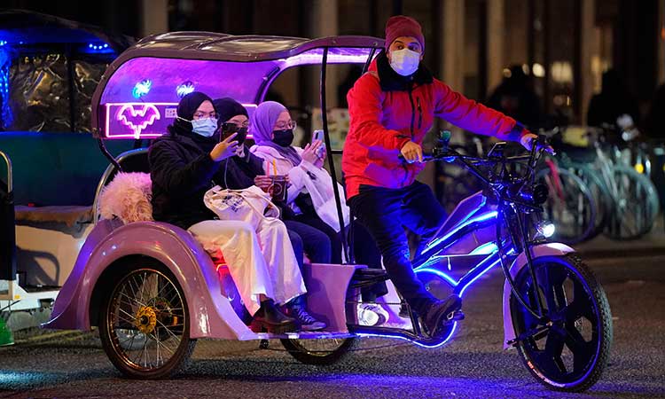 People ride in a bike taxi near Leicester Square in London.  Associated Press