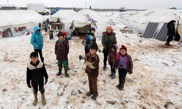 Internally displaced children stand on snow near tents at a makeshift camp in Azaz, Syria. Reuters