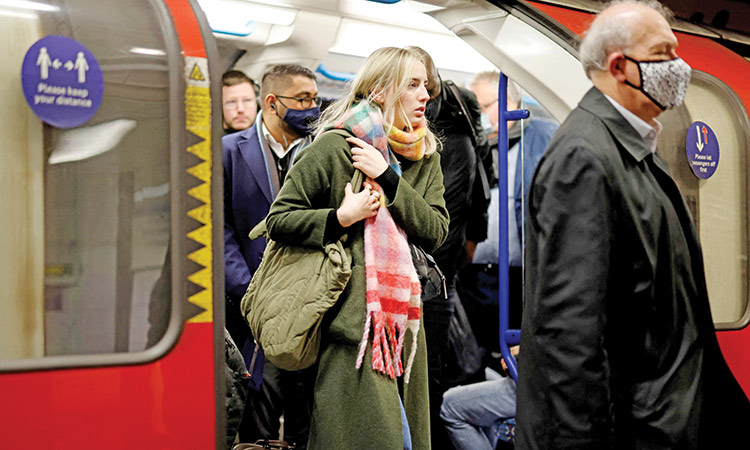 Commuters with and without face coverings get off a Transport for London (TfL) underground train in London. 