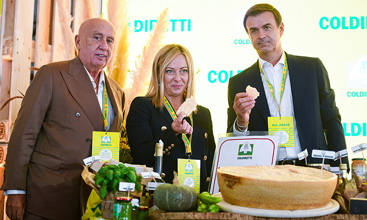 Giorgia Meloni tastes Parmigiano cheese with President of the Italian Farmers’ Association (Coldiretti), Ettore Prandini (right) and Coldiretti secretary-general Vincenzo Gesmundo on Oct.1, 2022 in Milan. AFP