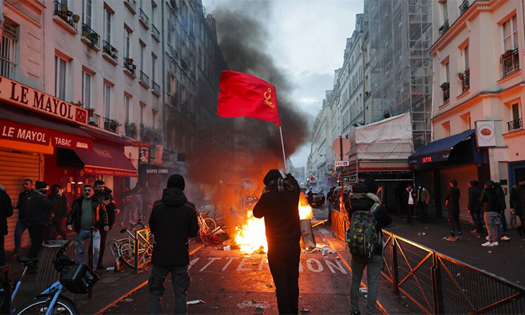 A member of Paris’ Kurdish community waves the Kurdish communist flags next to a barricade on fire at the crime scene where a shooting took place in Paris. AP