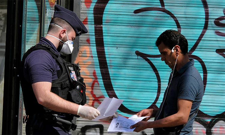 French Police officer wearing a face masks checks documents of a man in Paris. AP