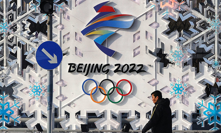 A man walks past the logo of Beijing 2022 Olympics in Beijing. AP