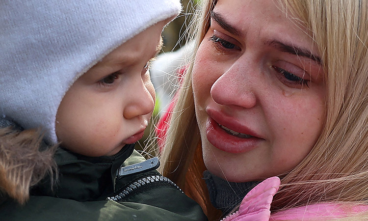 A woman is in tears as she holds her child after fleeing from Ukraine because of the Russian invasion as they arrived with a bus at the village of Moszczany near the border checkpoint at Korczowa, Poland. Reuters