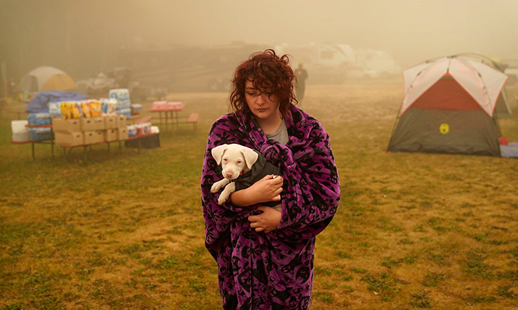 Shayanne Summers holds her dog, Toph, while wrapped in a blanket after several days of staying in a tent at an evacuation center in Oak Grove, Ore. AP