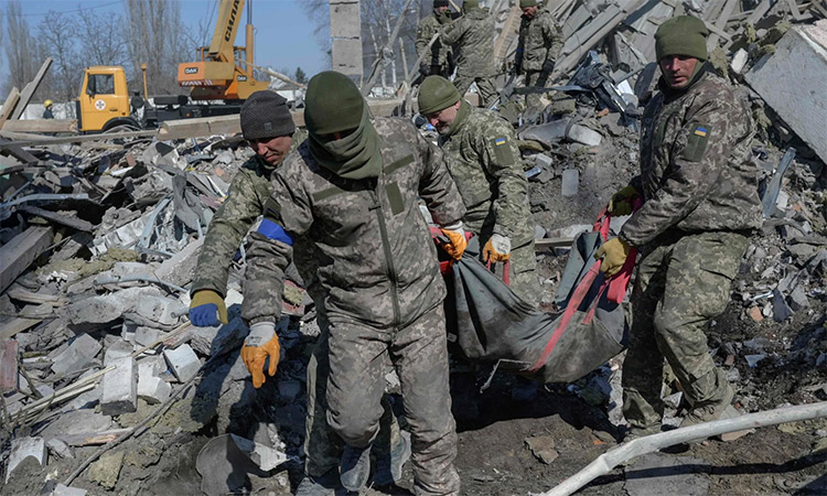 Ukrainian soldiers carry a dead soldier through debris at the military school hit by Russian in Mykolaiv, southern Ukraine.