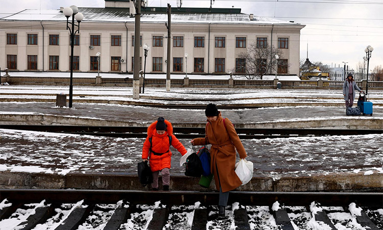 People fleeing Russia's invasion of Ukraine, cross train tracks to get to a train leaving for Poland. Reuters
