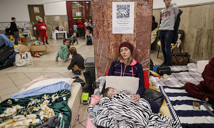 Julia rests with her son, Daniel, on a mattress laid inside the ticket office at the North Railway Station, after having fled Ukraine following the Russian invasion, in Bucharest, Romania, on Tuesday. Reuters