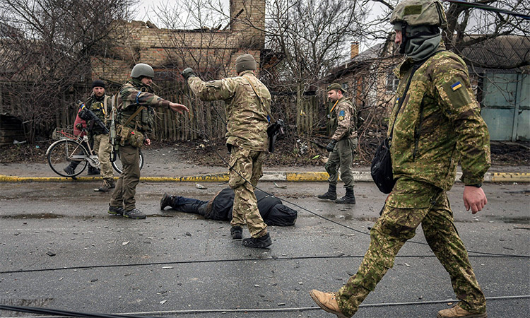 Ukrainian servicemen attach a cable to the body of a civilian while checking for booby traps in the formerly Russian-occupied Kyiv suburb of Bucha, Ukraine. AP