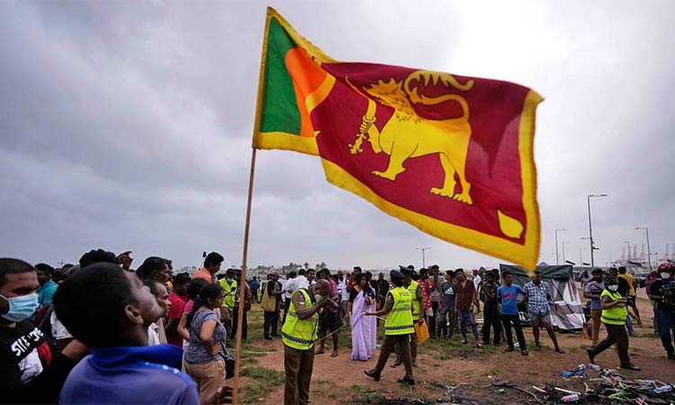 A Sri Lankan man holds a national flag as police officers conduct investigations into aftermath of clashes between government supporters and anti government protesters in Colombo, Sri Lanka. AP