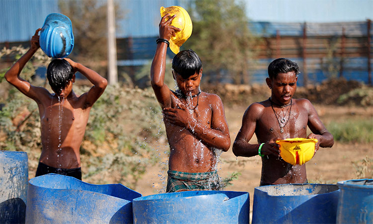 Workers use their helmets to pour water to cool off near a construction site on a hot summer day on the outskirts of Ahmedabad. Reuters