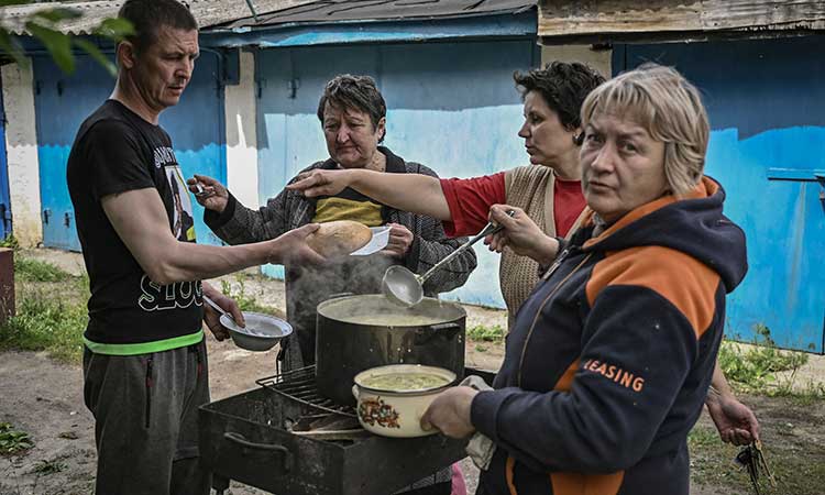 Residents of the city of Lysychansk cook food outside their houses, as the city is without electricity and water, in the eastern Ukrainian region of Donbas. AFP
