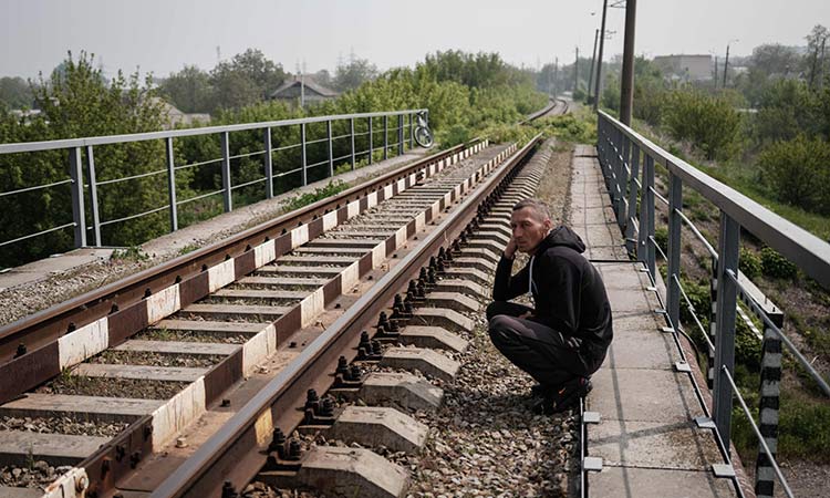 A pedestrian sits on a railway bridge over a river in Slovyansk, eastern Ukraine. AFP