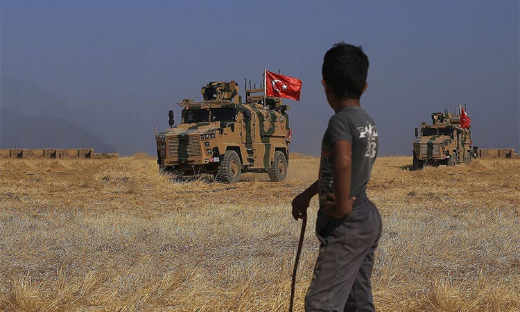 Turkish armored vehicles patrol as they conduct a joint ground patrol with American forces in the so-called "safe zone" on the Syrian side of the border with Turkey, near the town of Tal Abyad, northeastern Syria. File/AP