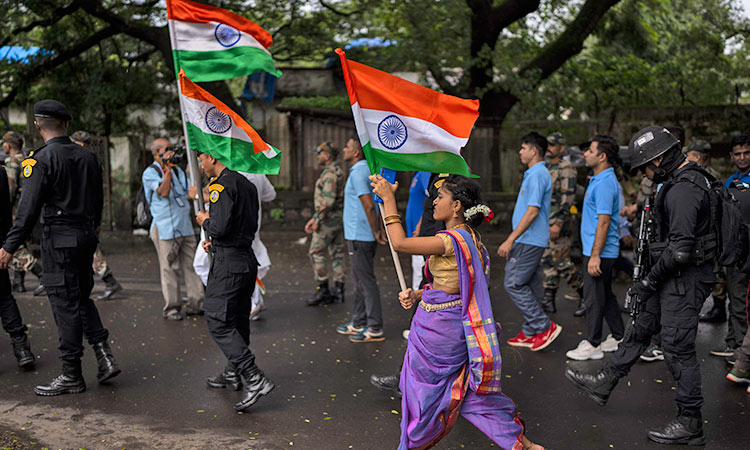 A girl walks, carrying the Indian flag, along with army soldiers during a ceremony to celebrate 75 years of India’s Independence in Mumbai, India.   Associated Press