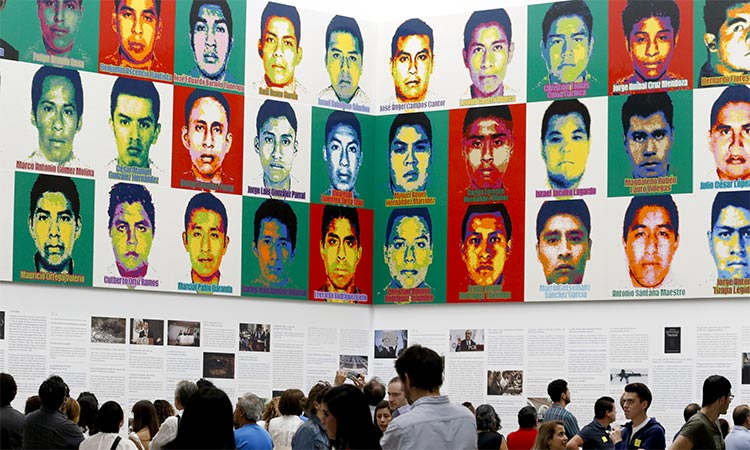 People stand under portraits of 43 college students in Mexico City. AP