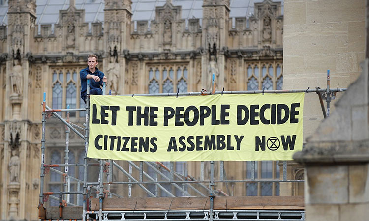 An Extinction Rebellion protester stands with a banner on the scaffolding inside the grounds of the Houses of Parliament in London. Reuters