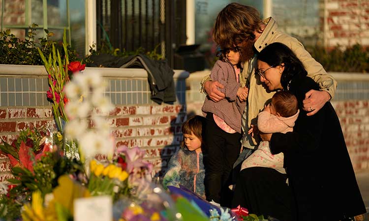 A family gathers at a memorial outside the Star Ballroom Dance Studio, the site of a mass shooting in Monterey Park, California. AP