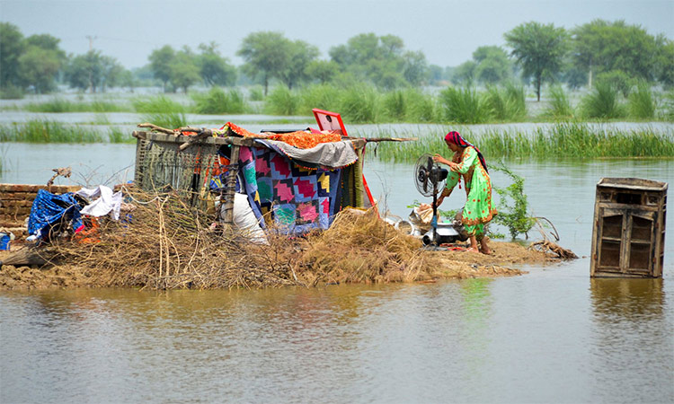 A woman taking refuge is seen with her belongings, following rains and floods during the monsoon season in Sohbatpur, Pakistan. File/Reuters