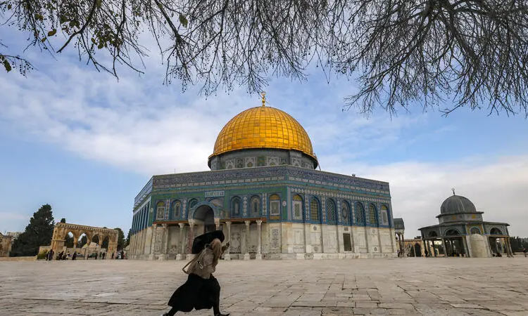 A woman walks near the Dome of the Rock shrine at the Aqsa mosque compound in the old city of Jerusalem. AFP