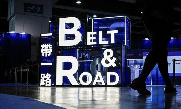 A man walks past a symbol of the Belt & Road Initiative.