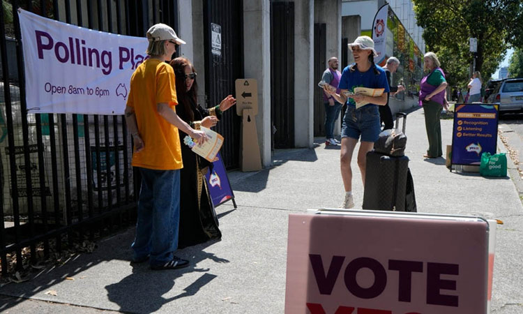 Volunteers talk with people coming to vote at a polling place in Redfern as Australians cast their final votes in Sydney.  File/Associated Press